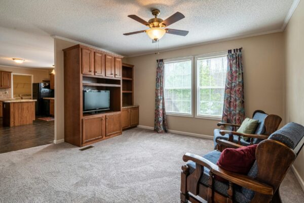 Spacious living room featuring a ceiling fan, large windows, and comfortable seating.