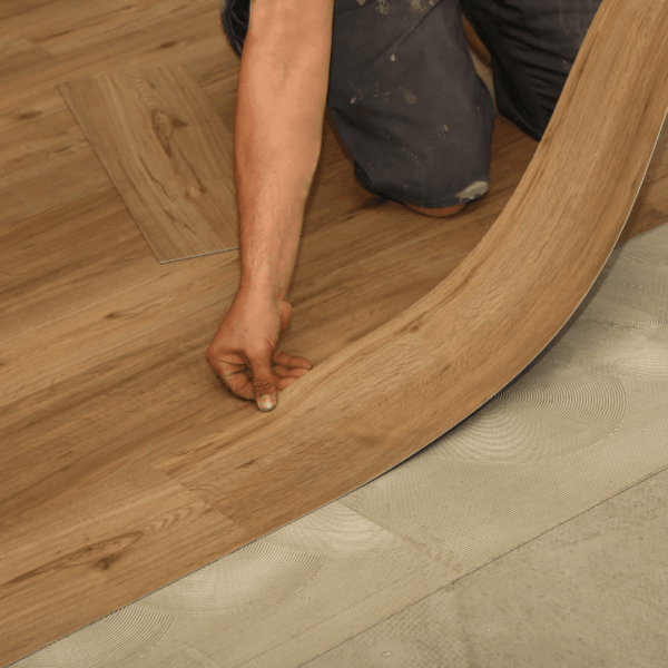 A person smoothly installing laminate flooring planks with a curved edge.
